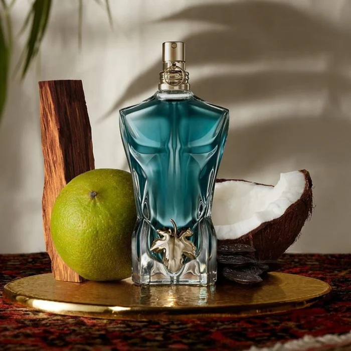 Perfume le beau de jean paul gaultier junto a frutas de sus notas olfativas